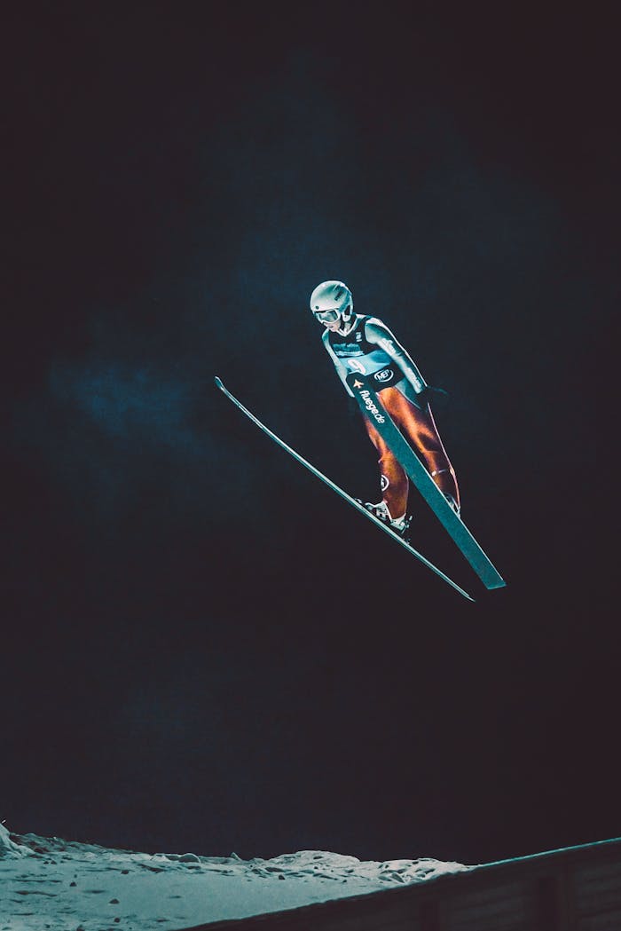 Dramatic night-time shot of a skier performing a ski jump mid-air, showcasing athleticism.